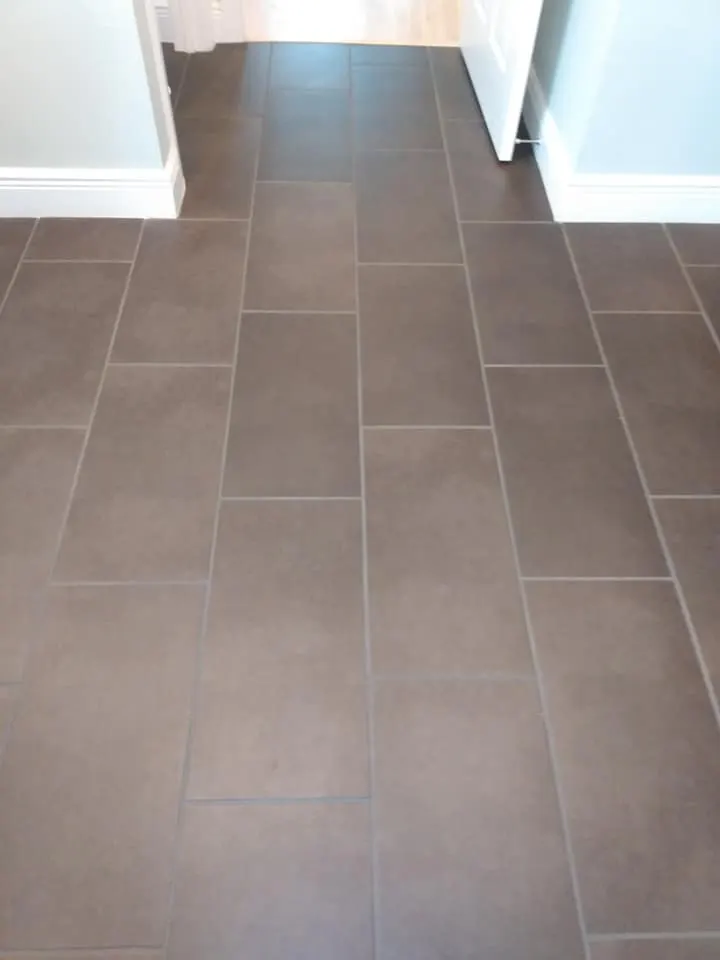 Dark tile floor with hazy, soiled grout before cleaning